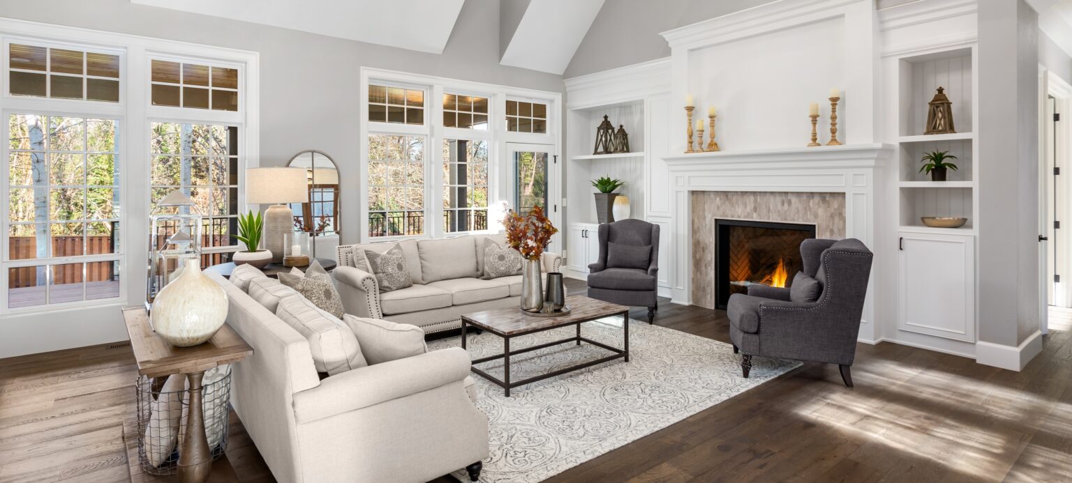 Beautiful living room in new traditional style luxury home. Features vaulted ceilings, fireplace with roaring fire, and elegant furnishings.