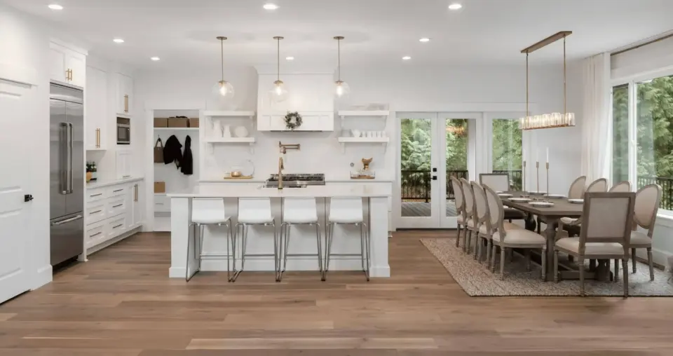 Professionally painted white kitchen interior with bright white cabinetry and trim, gold hardware accents, and adjoining dining room with dark wood furniture